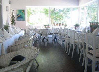 Ein heller Wintergarten mit weißen Möbeln und großen Fenstern.