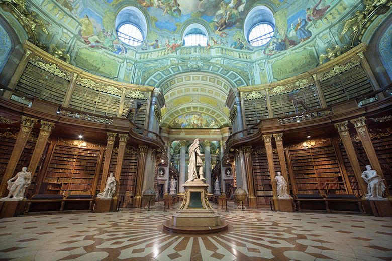 Prunksaal der Österreichischen Nationalbibliothek mit Statue und Deckenfresken.