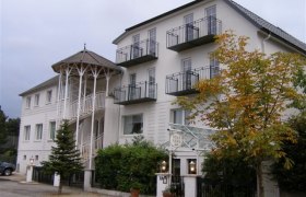 Ein mehrstöckiges Gebäude mit Balkonen und einem Eingang mit Säulen.