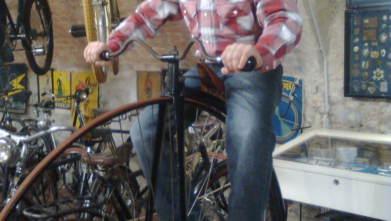 Ein Junge mit Hut sitzt auf einem Hochrad im Fahrradmuseum Schloss Vösendorf.