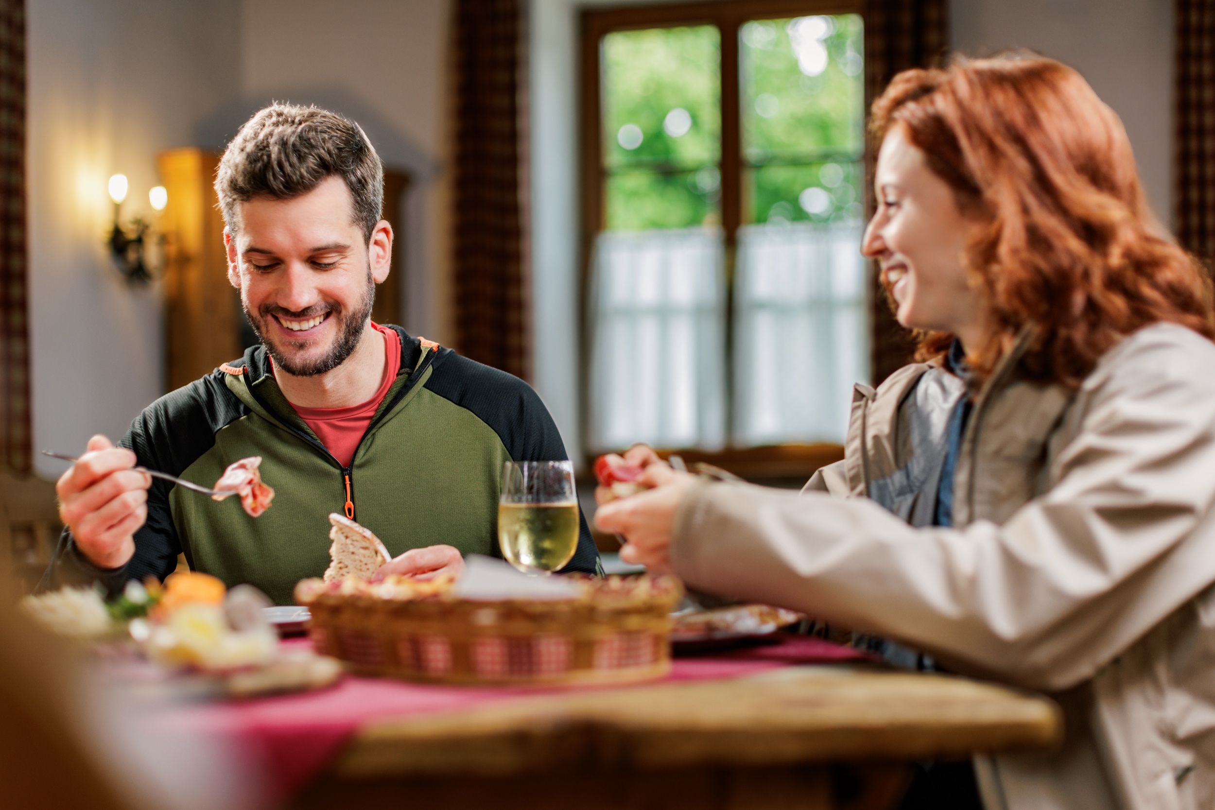 Ein Mann und eine Frau teilen sich eine Brettljause in einem Heurigen
