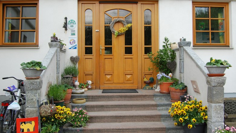 Vorderseite eines Hauses mit Holztür, Treppe und Blumendekoration.