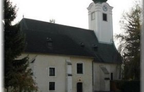 Church with tower and green roof in Schwadorf.