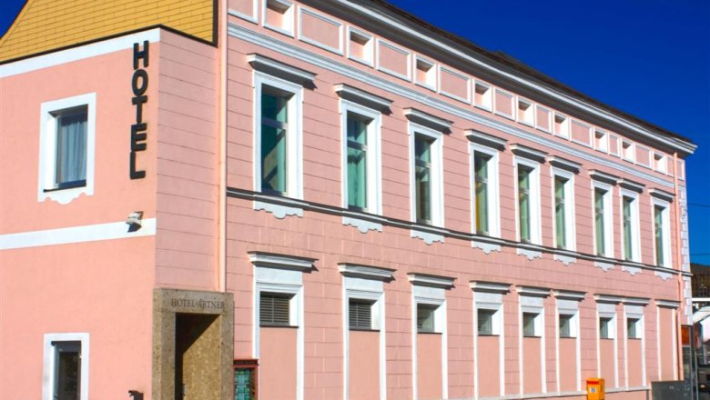 Ein rosa Gebäude mit der Aufschrift 'Hotel' an der Fassade.