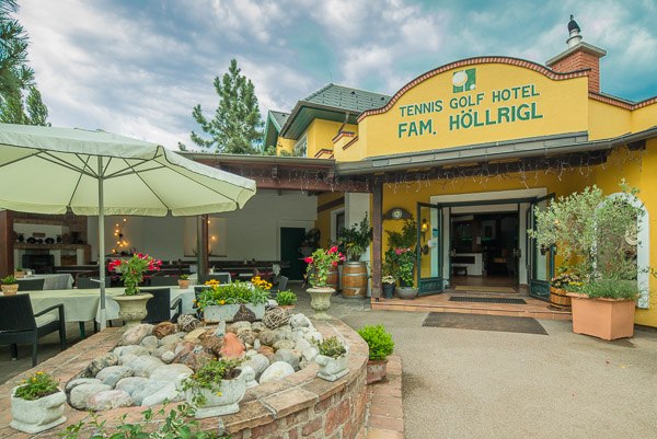 Eingang des Tennis Golf Hotels Höllrigl mit Terrasse und Pflanzen.