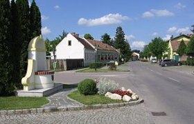 Straße in Mitterndorf an der Fischa mit Häusern und Denkmal.